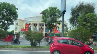 Vietnam görüş alanında kırmızı araba Saigon yeşil ağaçlarının arasında farklı evlerin önünden geçiyor şehir merkezinde güzel bir çeyrek tabela var. Vietnam Ho Chi Minh 06.06.2024