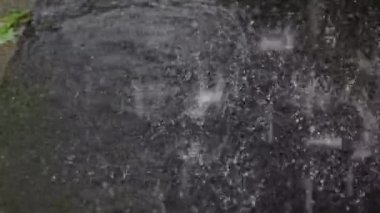 Yaz mevsiminde ağır yağmur damlalarının asfalt üzerindeki su birikintilerine düşüşü yavaş çekimde gerçekleşiyor. Şiddetli yağmur, yağmur mevsimi. yağmur birikintisi