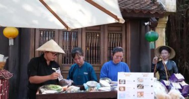 Vietnam şapkası takan dört kişi sokak yemeği hazırlıyor. Vietnamlı yemek satıcıları. Phu Quoc Adası Vietnam 06.15.2024