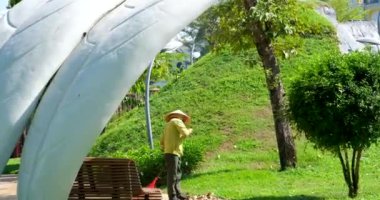 Vietnamlı temizlikçi parkta. Asyalı fakir adam Vietnamlı şapkası sokakları temizliyor. Yüksek kalite 4k görüntü