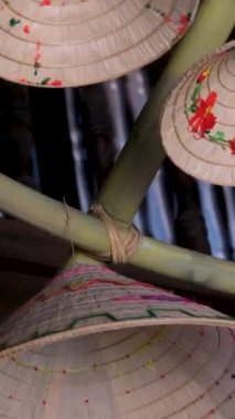 Duvarda Vietnam şapkalarıyla süslenmiş bir süs var. Güneşli bir plajda gelişmekte olan bir çok farklı küçük ve büyük başlıklı renkli Vietnam şapkası koleksiyonu. Vietnam şapkaları.