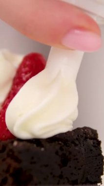 Çikolatalı Brownie, çilekli ve kremalı. Çilekleri kremayla süsleyin. Çileklerin üzerine krema döken çikolatalı brownie tatlısından leziz yemekler.