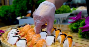 Taş siyah tahtada lezzetli Japon suşi ruloları. Çubuklar setten suşiyi alıp soya sosuna batırır. Kırmızı havyarlı, balıklı, Philly peynirli ve çubuklu çeşit çeşit suşi..