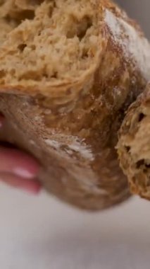 Sinematik çekim: ekmek kırın. Masada bir somun taze ekmeği kıran kadın eli manzarası. 4 bin. Ağır çekim. Kara ekmeği kır.