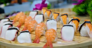 Taş siyah tahtada lezzetli Japon suşi ruloları. Çubuklar setten suşiyi alıp soya sosuna batırır. Kırmızı havyarlı, balıklı, Philly peynirli ve çubuklu çeşit çeşit suşi..