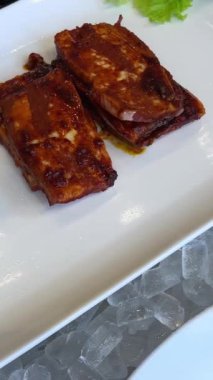 Beyaz yüzeyde ızgara et kesmek için metal bıçak kullanarak elinizi kapatın. Pembe sulu malzeme üzerine turuncu desenli eşkenar dörtgen. Yemek hazırlama kavramı. marine edilmiş ızgara et.