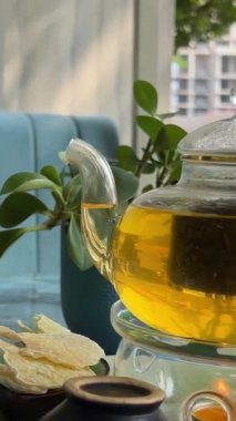 Beyaz çiçekli çay demleme işlemi, sıcak suda açılan güzel sarı çiçek, yeşil yapraklar, çay seremonisi. şeffaf cam çaydanlık. Mumlar yanıyor.