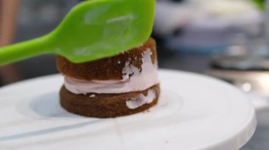 Palet bıçağı kullanarak, kremadan yapılmış bir çiçekle bento pastası süsle. Seçici odaklanma. Yüksek kalite 4k görüntü