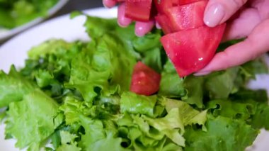 Kız, salatalık, salatalık, fındık ve vejetaryen için bej arka planda beyaz tabak tahta kaşıkla dilimlenmiş kiraz domatesli sebze salatası ekliyor. Domates salatası ekle.