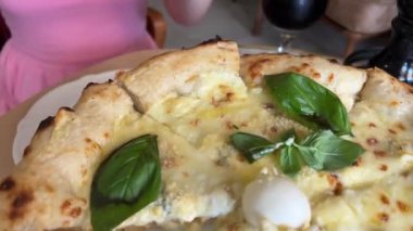 Peynirli bir dilim sıcak İtalyan pizzası. Fesleğenli dört peynirli pizza. Kadın dört peynirli fesleğenli peynirli pizza yiyor. Yüksek kalite 4k