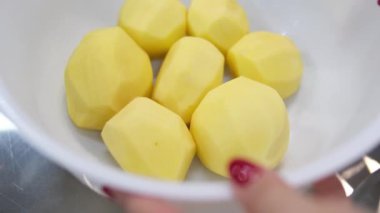 Mutfaktaki bir bardak suda çiğ patates, evde akşam yemeği hazırlama süreci, mutfakta bir bardak suda patates ve dişi patatesler. Yüksek kalite 4k görüntü.