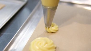 Profiterol üretimi süreci. Pasta poşetindeki hamur işlerini sıkıyorum. Kapatın. Yüksek kalite 4k görüntü