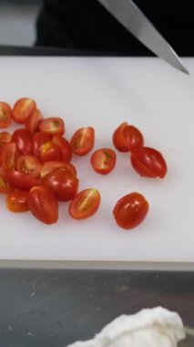 Kadın, yerli mutfağın tahta kesme tahtasıyla kiraz domatesi kesiyor. Yüksek kalite 4k görüntü