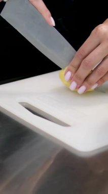 Patates kesmek. Bıçağı kapat, patatesi kes. sebze pişirmek. Yemek hazırlama. Kadın taze patates keser. Güzel manikürlü kadın eli ahşap mutfak tahtasındaki olgun patatesi keser.. 
