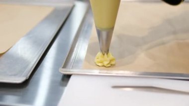 Profiterol üretimi süreci. Pasta poşetindeki hamur işlerini sıkıyorum. Kapatın. Yüksek kalite 4k görüntü
