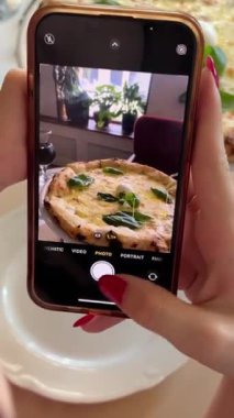 Fırında pişirilmiş lezzetli İtalyan pizzası. Peynirli pizza. Blogcu, restoranda leziz pizzanın videosunu cep telefonundaki mobil ağ üzerinden canlı yayında çekiyor
