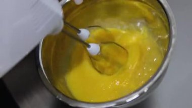 Yumurta çırpmak için karıştırıcıyı metal bir kaseye batırmak. çırpılmış yumurta ve karıştırıcı.