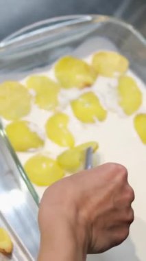 Kadın cam bir tabakta patates katmanına tavuk eti koyar. Evde yemek pişirmek. tavuklu patates graten.