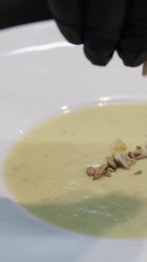 Ocakta kremalı sebze çorbası hazırlayan ve rendelenmiş çedar peyniri çırpan bir kadının kısa şarjörünü yap. Izgara peyniri sıcak sebze çorbasına ekliyorum.