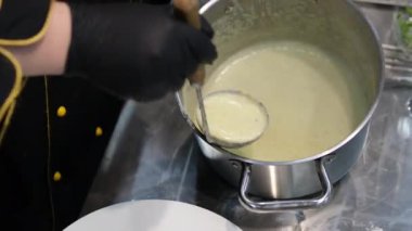 Ocakta kremalı sebze çorbası hazırlayan ve rendelenmiş çedar peyniri çırpan bir kadının kısa şarjörünü yap. Izgara peyniri sıcak sebze çorbasına ekliyorum.