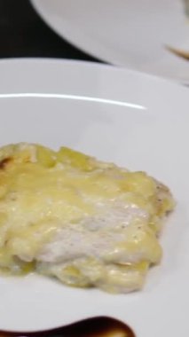 Kadın cam bir tabakta patates katmanına tavuk eti koyar. Evde yemek pişirmek. tavuklu patates graten.