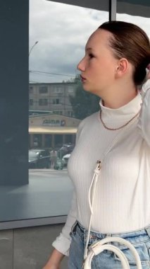Kızın dikilip arkadaşını beklediği, ağzını kapattığı ve esnediği ön manzara. Geceleri şehirde tek başına olmak. Bina ve gece lambası arka planı. Şehir gecesi konsepti. sokak binası