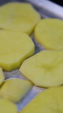 Dişi eller fırına yağlı, tuzlu ve karabiberli haşlanmış altın patatesli tavayı koyar. Fırında kızartılmış patates pişirme süreci. Patates pişir.