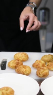 Kadın elleri beyaz tabağa somonlu profiterol koyuyor. Profiterol yap.
