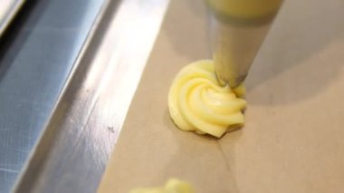 Choux ya da profiterol pişirirken, kadın elleri hamuru torbadan fırın kağıdına sıkıştırır, genel görünüm. Çikolatalı craquelin ile kremalı ve çilekli choux pişiriyorum. Vanilyalı choux. Yüksek kalite 