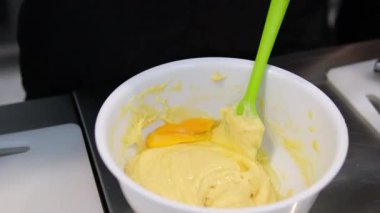 Choux ya da profiterol pişirirken, kadın elleri hamuru torbadan fırın kağıdına sıkıştırır, genel görünüm. Çikolatalı craquelin ile kremalı ve çilekli choux pişiriyorum. Vanilyalı choux. Yüksek kalite 