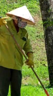 Vietnamlı temizlikçi parkta. Asyalı fakir adam Vietnamlı şapkası sokakları temizliyor. Yüksek kalite 4k görüntü