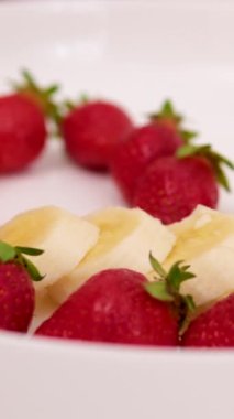 Çilekli ve muzlu milkshake ya da blender 'da smoothie pişiriyorum. Blender 'a olgun meyveler döküyorum. Ağır çekim. Sağlıklı içki konsepti. bir kalple çilek ve muz koy.