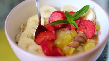 Muzlu çilekli yulaf ezmesi naneli ballı ananas parçaları ve tabakta kepçe badem sağlıklı beslenmeye iyi gelir. Yüksek kalite 4k görüntü