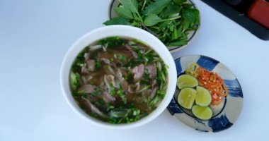 PHO BO Vietnamlı Biftek Çorbası. Asya çorbası sokak yemeği yapıyorum. Adam çatal ve kaşıkla fast food yiyor. Eller metalik çatal bıçak takımını tutuyor. Yüksek kalite 4k görüntü