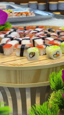 Asya mutfağı, yemek konsepti. Yaklaştın. Elinde maşa olan eller, sokaktaki gece pazarında suşi seçiyor. Suşi büfesi