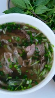 PHO BO Vietnamlı Biftek Çorbası. Asya çorbası sokak yemeği yapıyorum. Adam çatal ve kaşıkla fast food yiyor. Eller metalik çatal bıçak takımını tutuyor. Yüksek kalite 4k görüntü