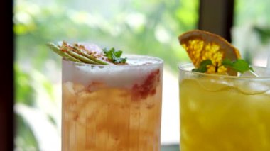 Guava ve portakallı yaz kokteylleri pencerenin yanındaki masada kurutulmuş meyve ve naneli pipetli buzlu içecekler var. Yüksek kalite 4k görüntü