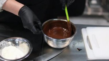 Çikolatalı pasta yapma sürecinde adım adım. Kadın eli yumurta ve tereyağını karıştırıcı ile karıştırır. Çikolatalı browni hazırlama işlemleri masanın üzerinde. yatay. 