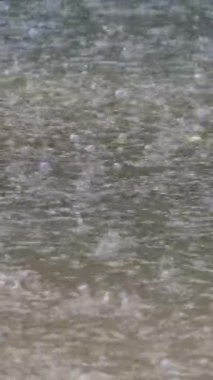 Yağmur damlaları temiz zemine düşer. Akan bir su birikintisine yağmur