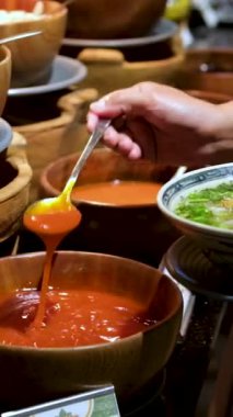 Vietnam 'daki büfede pho çorbasına domates sosu ekleyin. Bir kadın kaşıkla ketçapı pirinç vermicelli ile birlikte et suyuna katıyor. Yüksek kaliteli FullHD görüntüler