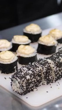 Kepli ve peynirli suşi, aşama aşama pişmiş rulo suşi. Yakından yemek pişirir. Bir şef suşi yapar ve pirinç, kırmızı balık, avokado ve Philadelphia peynirinden rulo yapar.. 