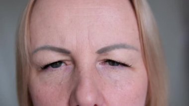 Kaşlarını çatan ve kaşlarını buruşturan bir kadın. 4k 'lık filmi yavaş çekimde çeker. Yüz ifadeleri konsepti. Kaşları hareket ettir Alnının altından bak