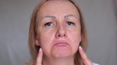 Yüzünün üst kısmı yaşlanmış, üzgün, yaşlı, kahverengi gözlü, maskara bakışlı yaşlı bir kadının yakın çekimi. Makyajlı, cildinde kırışıklıklar olan son sınıf model bir kadın. Kırpılmış atış