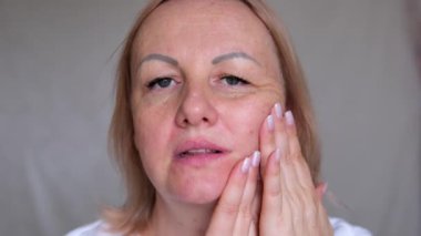 Yüzünün üst kısmı yaşlanmış, üzgün, yaşlı, kahverengi gözlü, maskara bakışlı yaşlı bir kadının yakın çekimi. Makyajlı, cildinde kırışıklıklar olan son sınıf model bir kadın. Kırpılmış atış