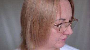 Gözlüğünü tak. Gülümseyen iş kadını. Evde dizüstü bilgisayarda çalışıp gözlük takıyor. Sıradan bir kadın profesyonel bilgisayar aygıtı üzerinde çalışıyor. Merkez ofis konsepti. Uzak serbest çalışma