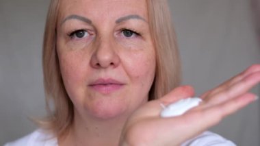 Güzel surat. Doğal makyajlı kadın yüzü. Genç ve güzel bir kadın taze nemlendirilmiş cilde dokunuyor. Deri bakımı konsepti. Yüze krem sür