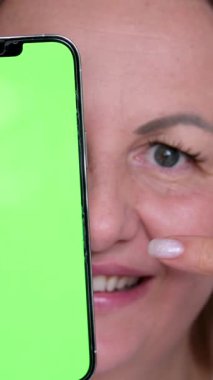 Cep telefonu reklamcılığı yapan bir kadın elinde akıllı telefon ve yeşil ekranlı içeriği izliyor. Yüksek kalite 4k görüntü