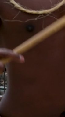 Boynunda esmer tenli bir adamın güçlü elleri elinde kemiklerden bir kolye bir davul sanatçısının saç tüyleriyle Papuan 'ı sahnelemesi. Yüksek kaliteli FullHD görüntüler