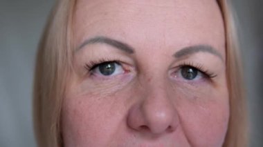 Güzel bir kadının yüzünü kapatın kameraya bakın, geniş beyaz bir gülümsemesi ve mükemmel dişleri var. Göz kamaştırıcı kadın portresi, güzellik prosedürü kaş kaplaması, cilt bakımı. 