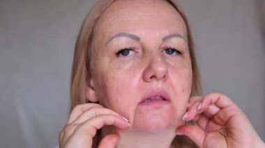 Yüzünün üst kısmı yaşlanmış, üzgün, yaşlı, kahverengi gözlü, maskara bakışlı yaşlı bir kadının yakın çekimi. Makyajlı, cildinde kırışıklıklar olan son sınıf model bir kadın. Kırpılmış atış